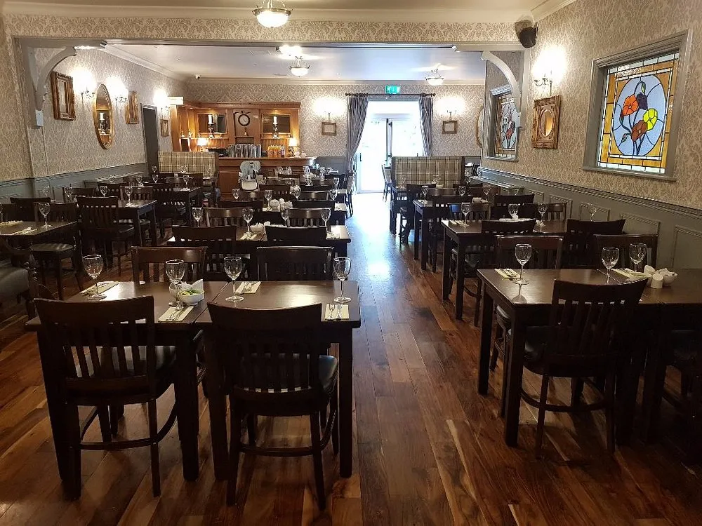 The restaurant dining room with dark wood tables and stained glass